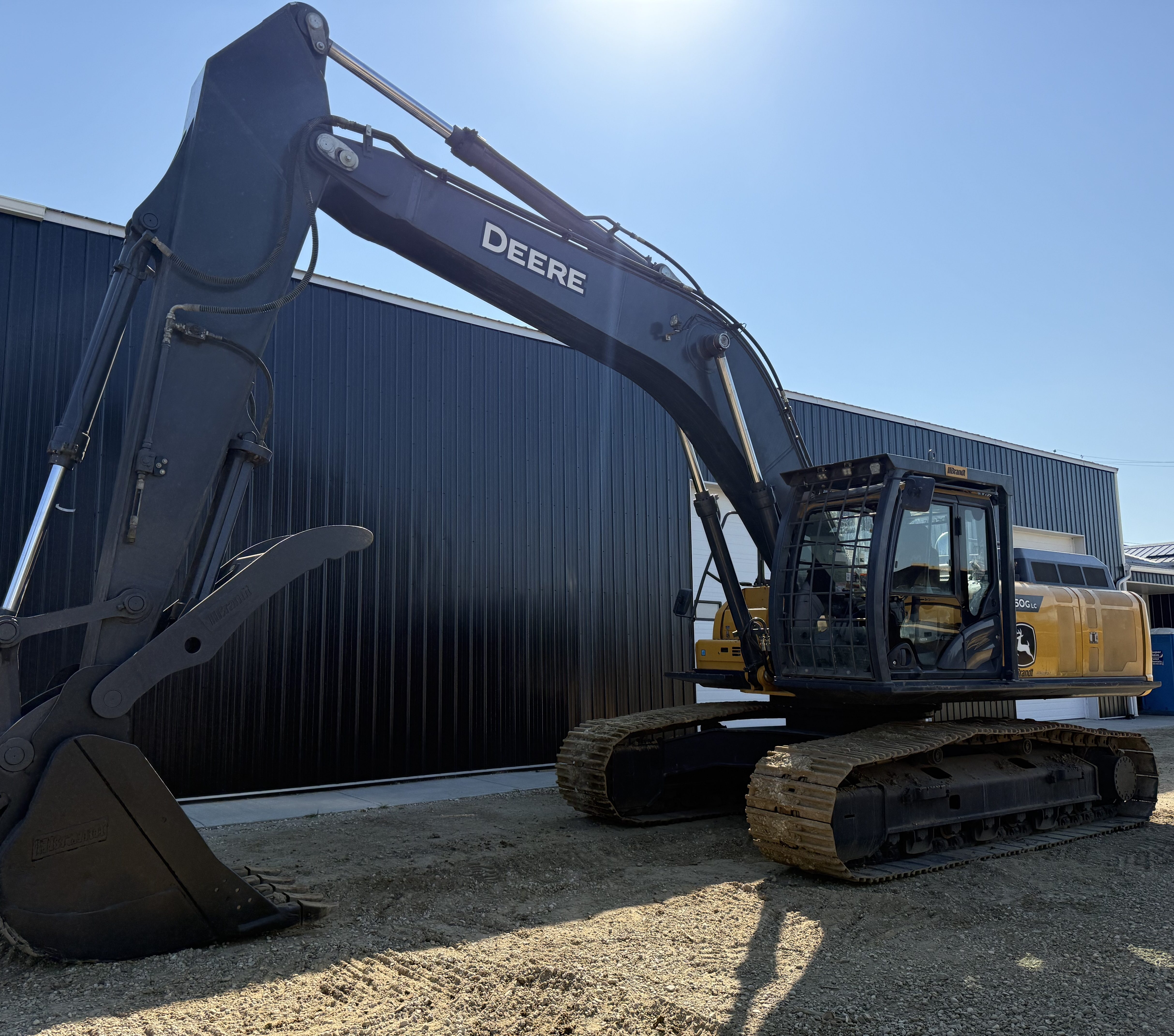 An excavator side-on, boom high, blue sky