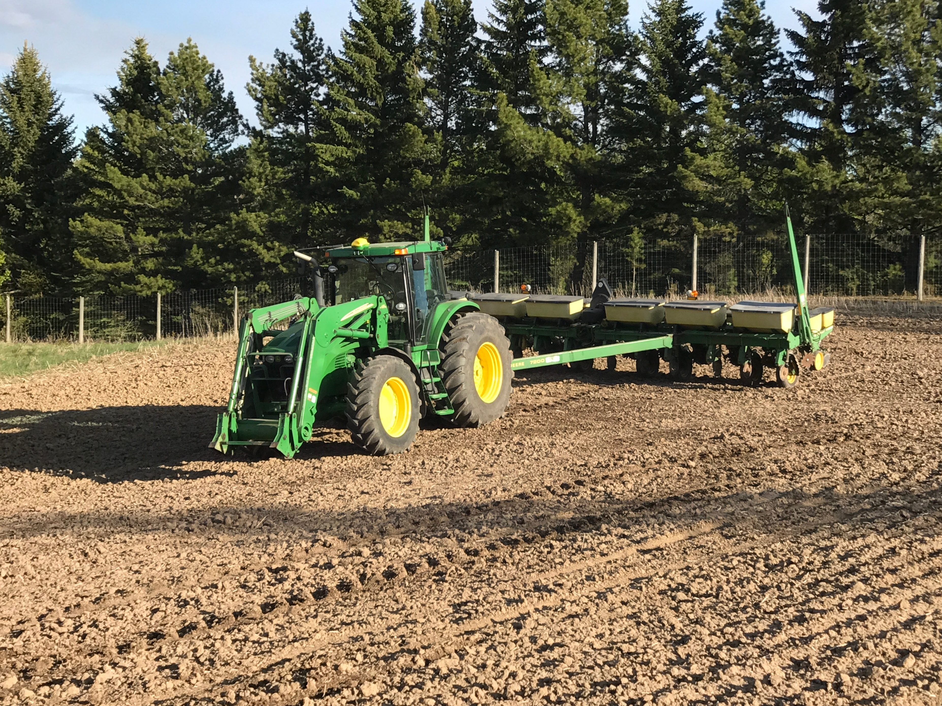 A tractor pulling a planter across a field in spring